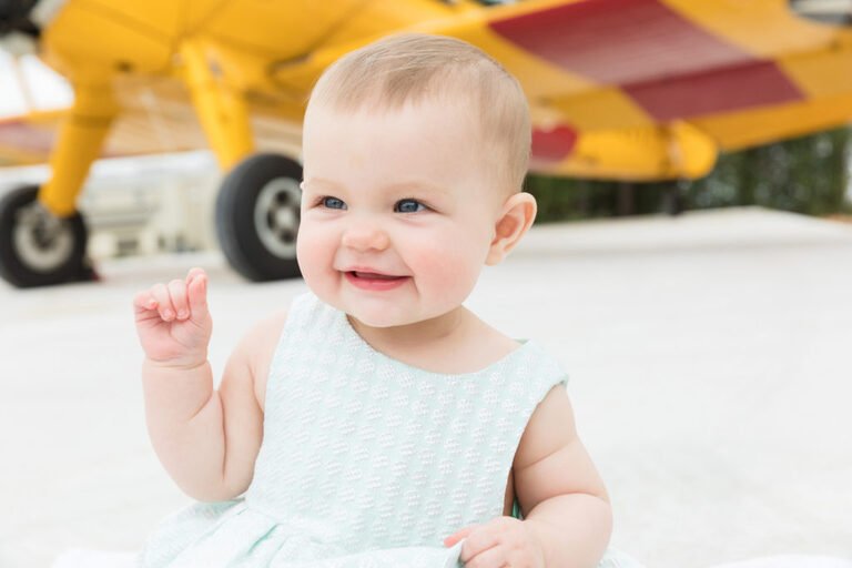 Six month old in front of an airplane at Conroe Regional Airport for her baby plan