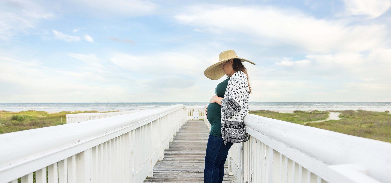 Expecting mother standing on a dock on Galveston island beach