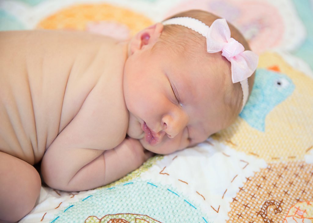 Photo of a two week old baby girl on a quilt taken by a Newborn photographer in Houston.