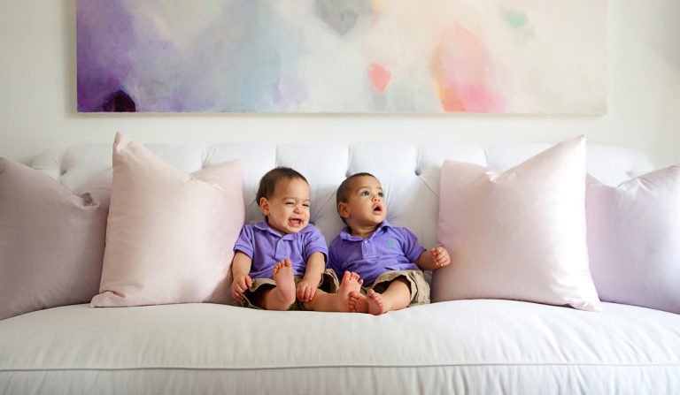 Lifestyle Photography - One year old twin boys sit on a white couch