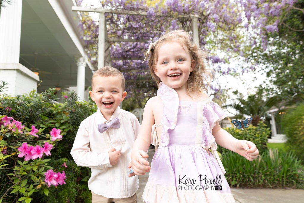 Four year old twins under wisteria during spring in Conroe TX