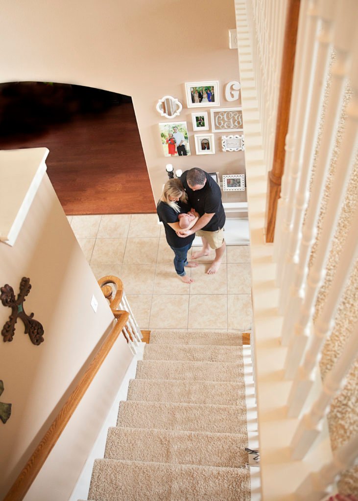 Woodlands Lifestyle photos - new parents with their baby at the bottom of a staircase