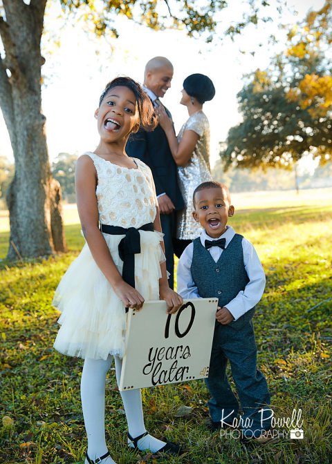 Kids pose in front of parents with a sign that says "10 years later..." in a photo by Kara Powell Photography.