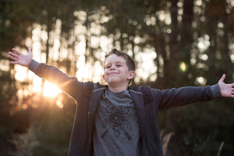 Boy with his arms spread in the woods