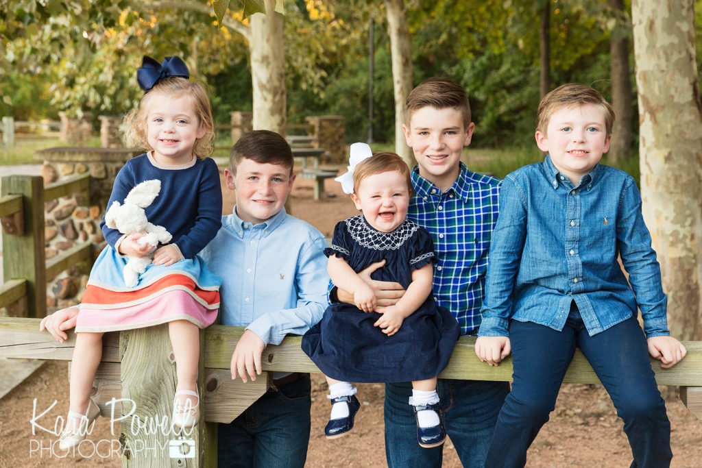woodlands family photographer - 5 cousins sit and stand along a wood fence