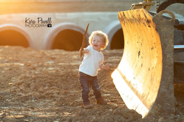 woodlands children photographer - boy plays with a stick in a construction site.