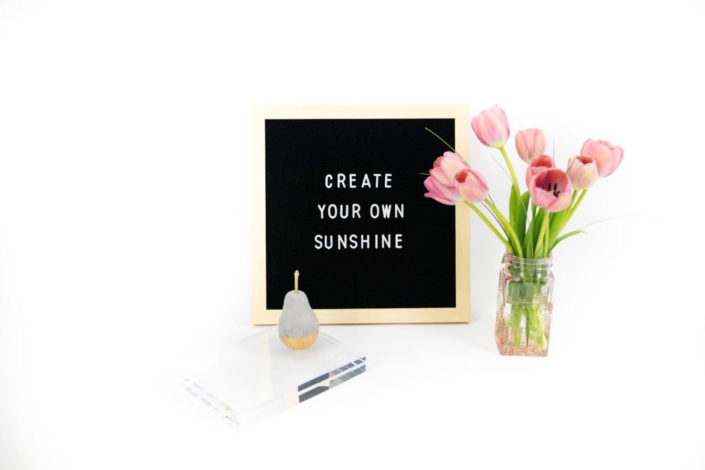 Image of the words "Create your own sunshine" with tulips and a concrete pear.