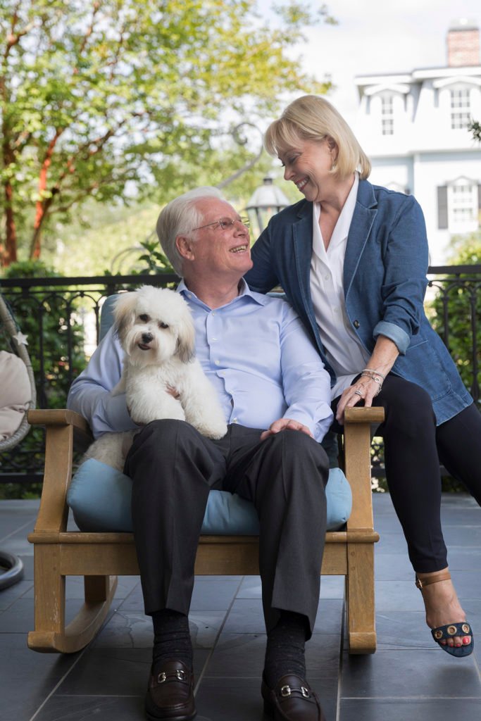 A couple and their small white dog pose on their patio for an in home photo session.