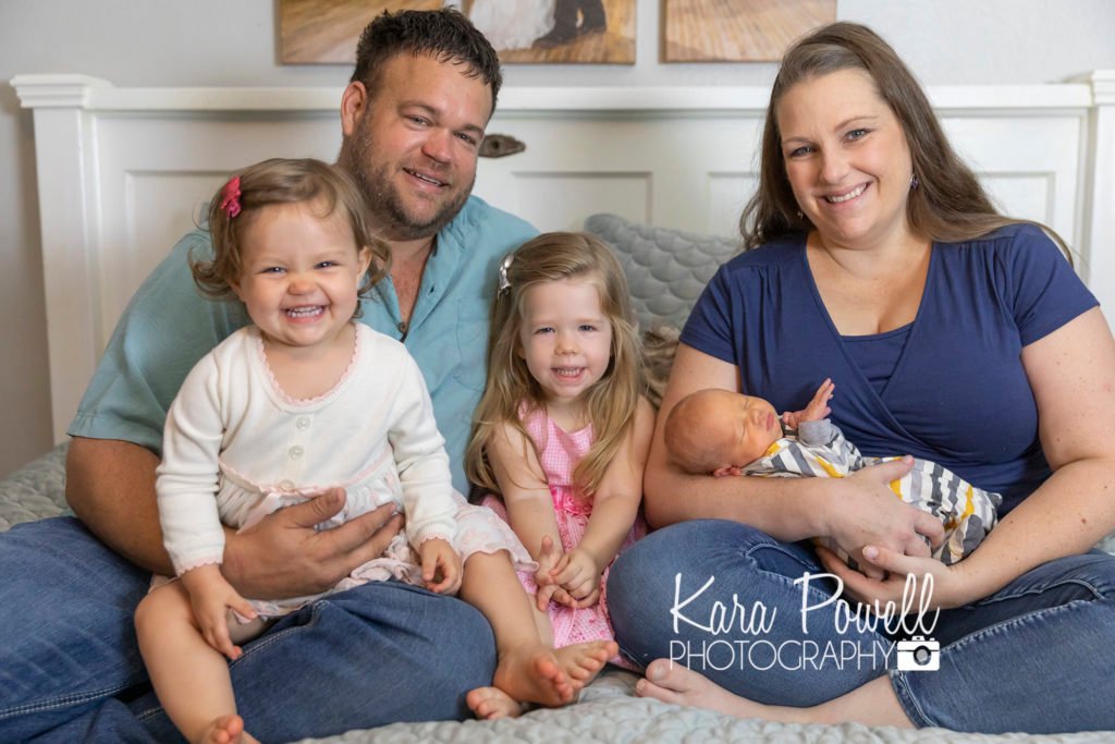 Family with two toddler and a newborn pose together with a Newborn photographer in Huntsville TX