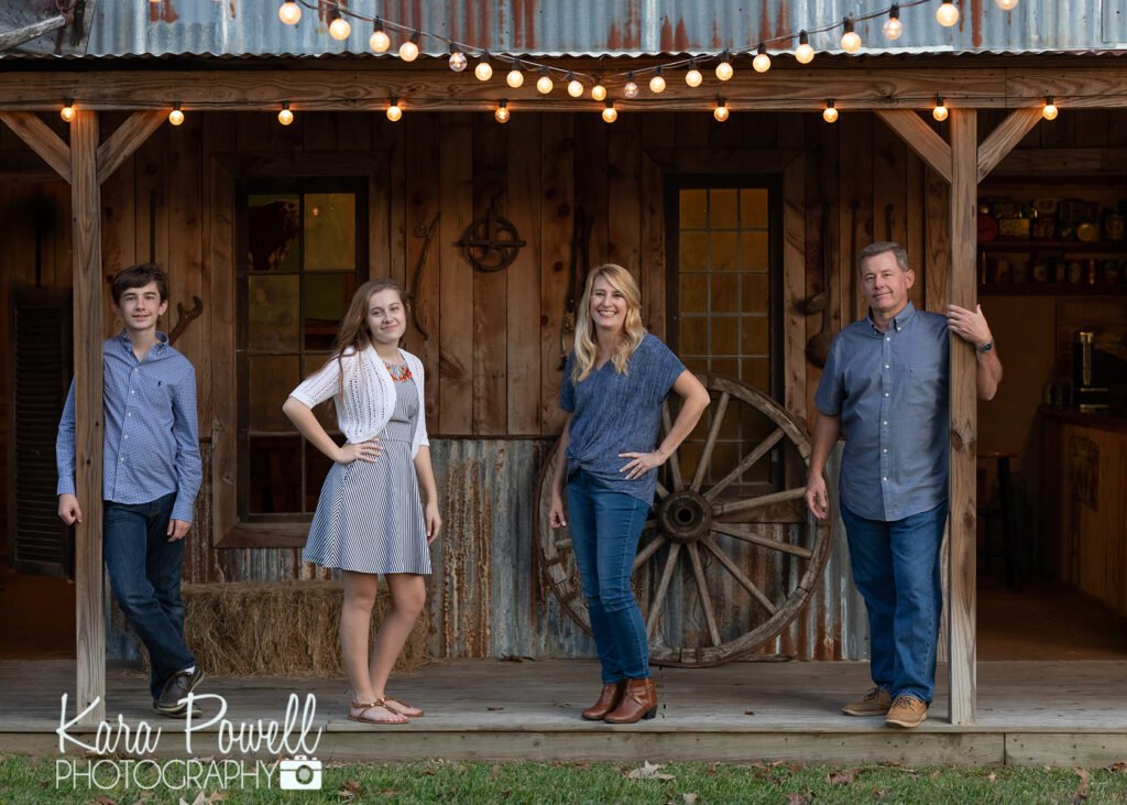 Family of four standing in front of a rustic wood building celebrating summers with your kids