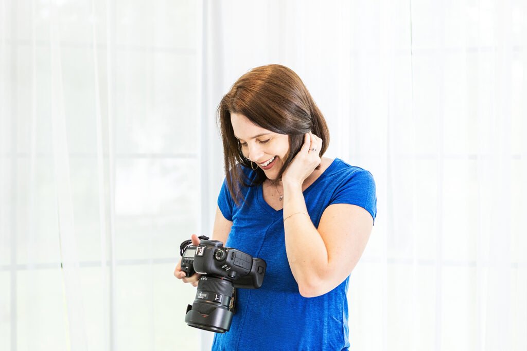 Photo of a woman holding a camera smiling down at it