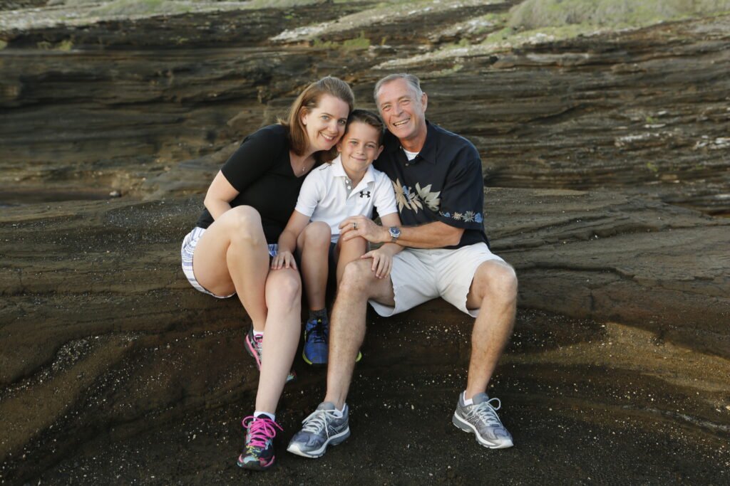 Family of three sitting on a rock in Oahu. You get what you pay for in family photos