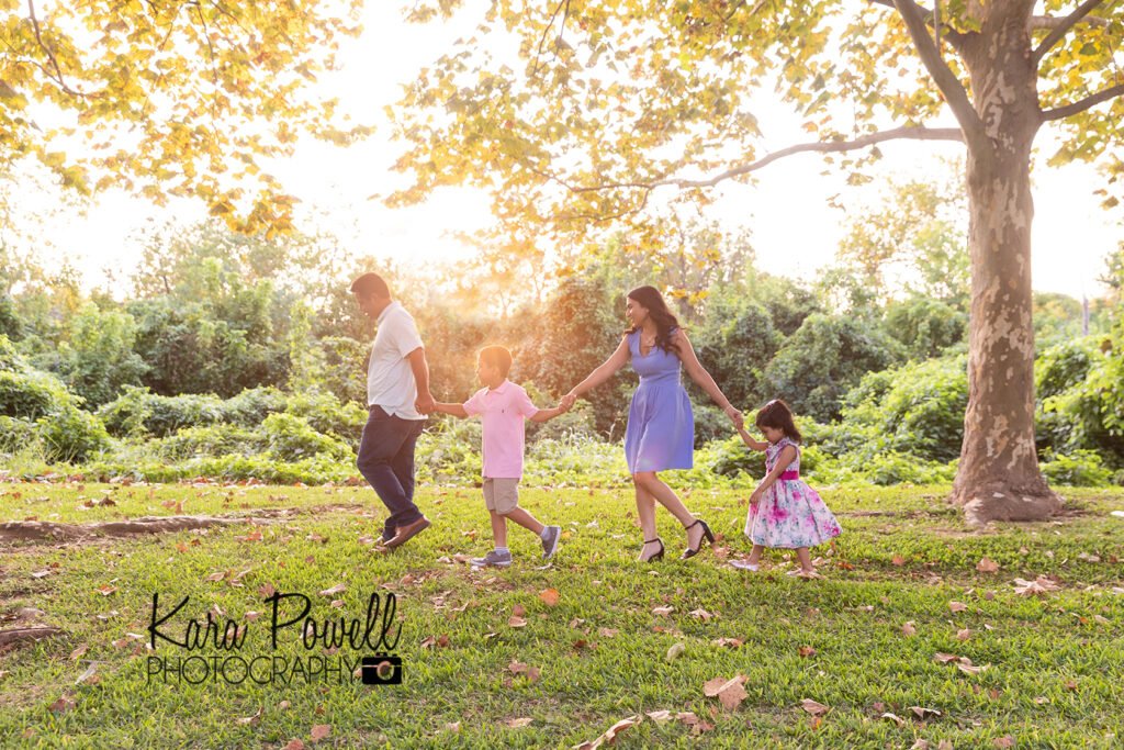 Family of four walks in a line through a fall colored park creating amazing images