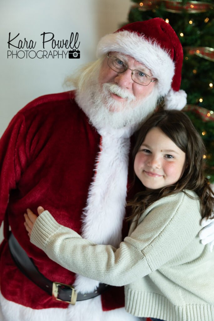 A tween hugs santa.