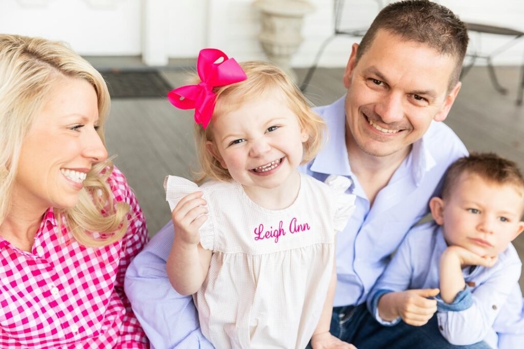 A family of four poses on the front porch of a historic home for their holiday cards.