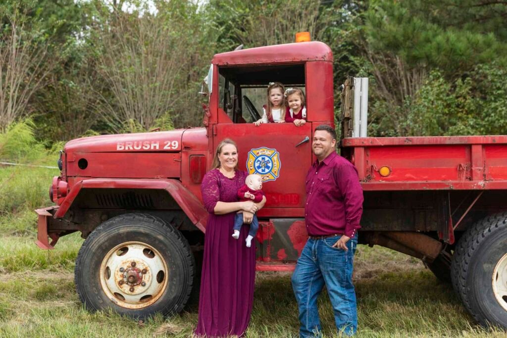 A family of 5 stands in front of an old fire vehicle for their tippy toes baby plan.