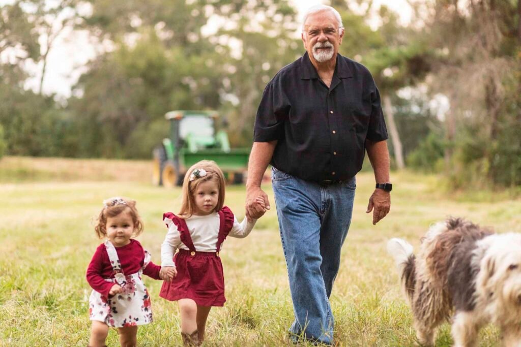 Grandpa leads his two grand daughters away from a tractor