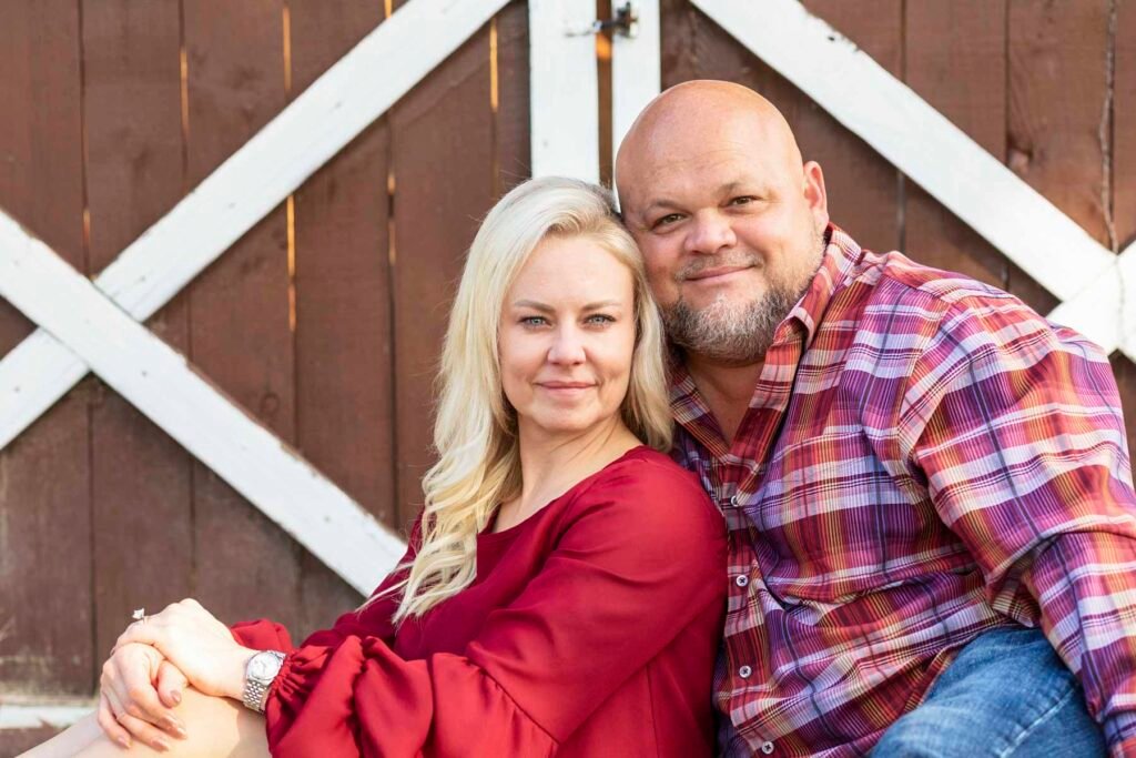 Husband and wife pose in front of barn doors