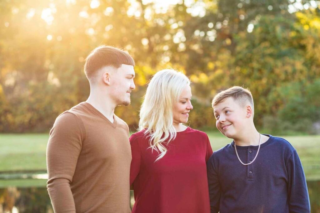 Two boys and their mom pose together in the fall