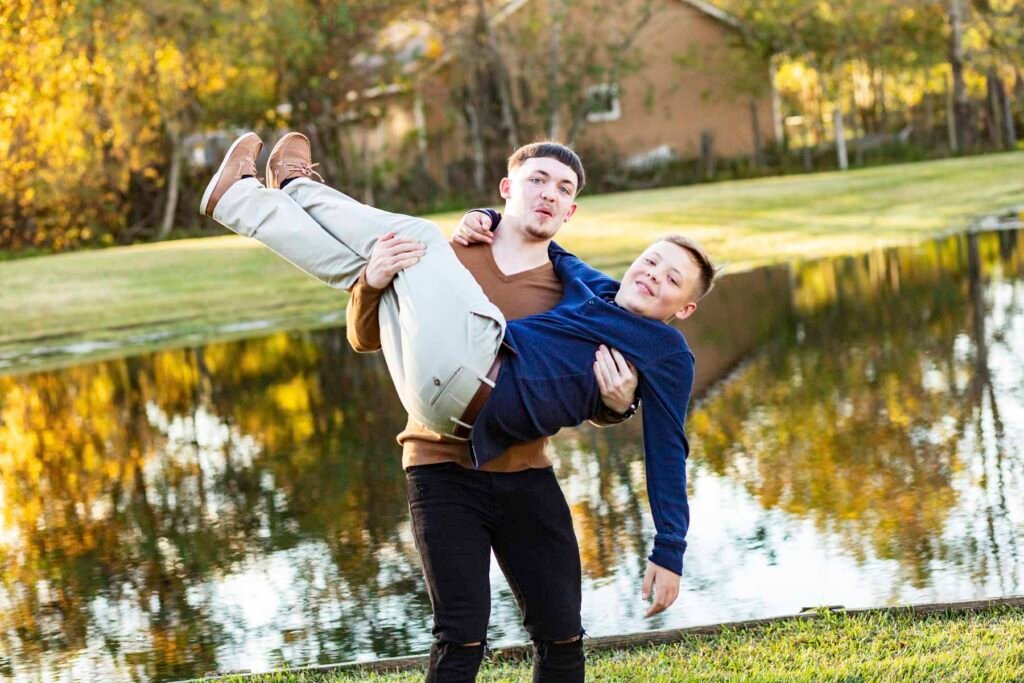 A brother fakes throwing his brother into a pond at their Townhall TX fall family session