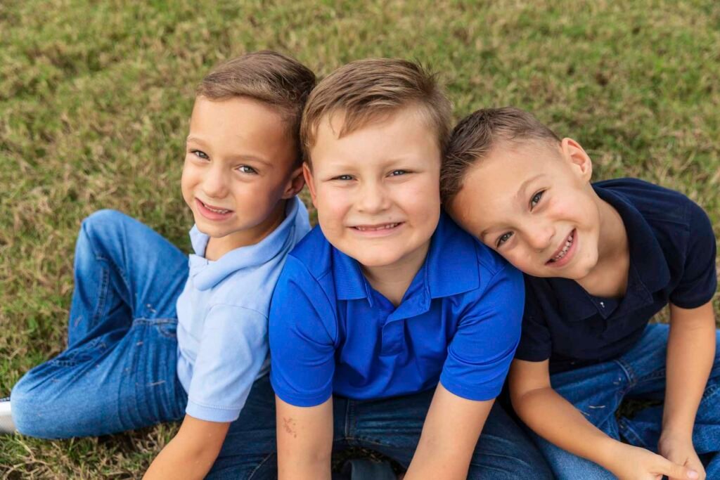 Three boys sit in the grass during a moment of calm in their fun crazy family photo session