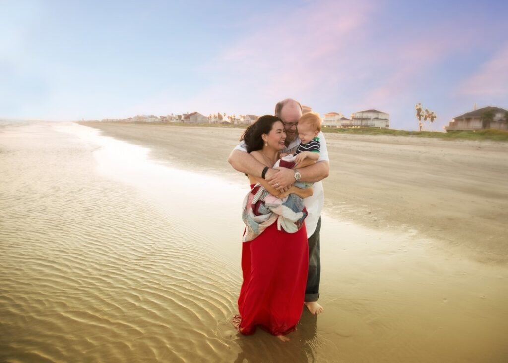 Family of three cuddling during a sunset on the beach of Galveston island