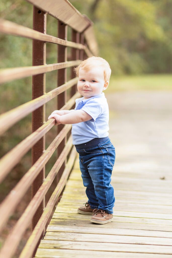 A little boy stands on a bridge for his one year birthday photo session