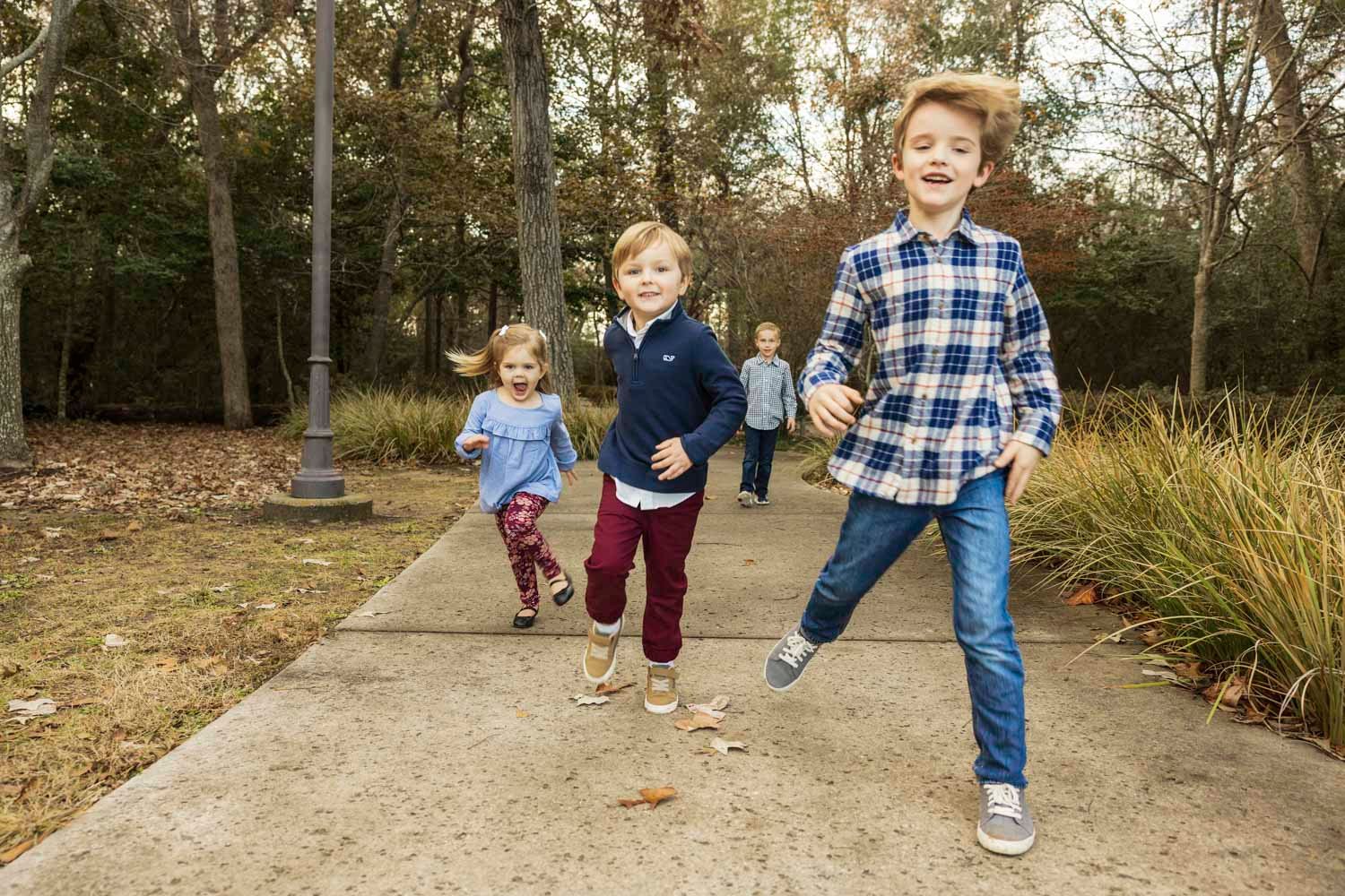 Cousins running through a park during fall in Tomball TX