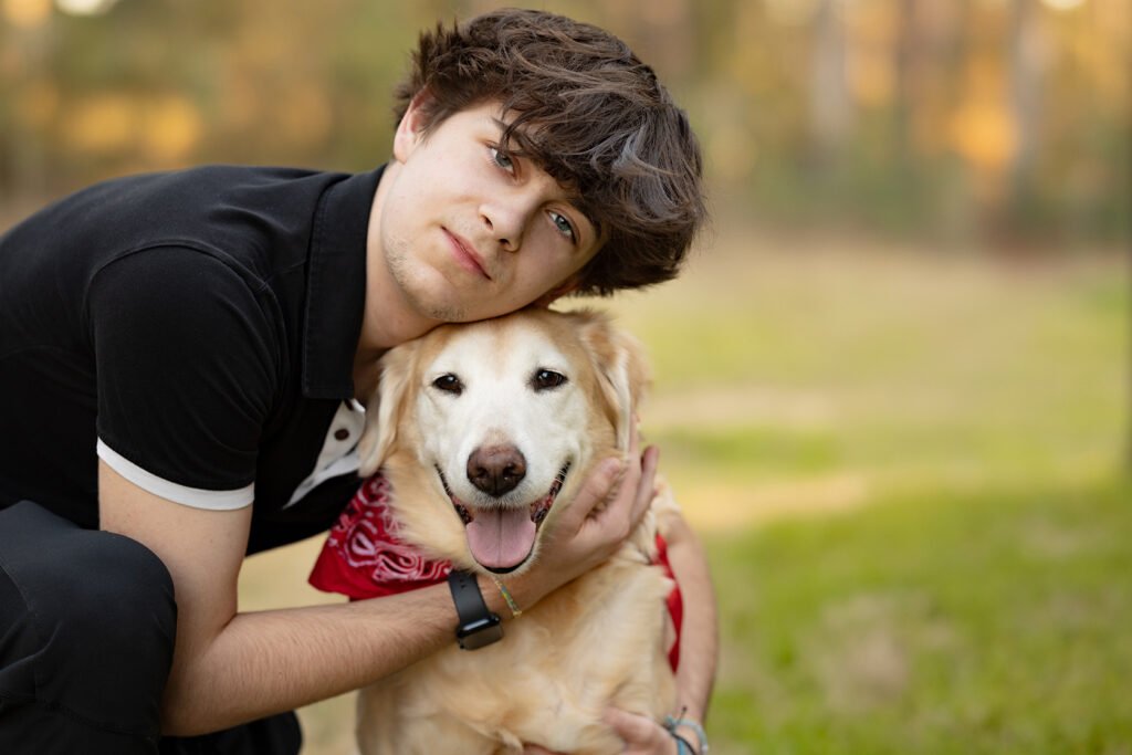 A boy holding his dog for a senior Pic in the woodlands, Texas.